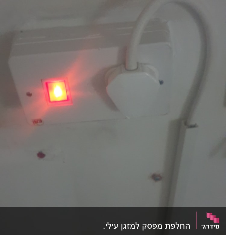 שקע חשמלי עם כבל מחובר ונורית אדומה דולקת